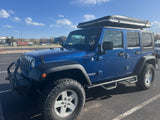 Blue Jeep Wrangler Unlimited with hard-shell rooftop tent, great for outdoor adventure or RV rental camping.