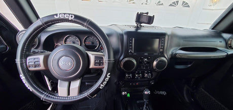 View from the driver's seat of a Jeep interior, featuring the dashboard, steering wheel, and screen, perfect for an RV rental.
