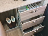 Inside an RV rental: compact kitchen storage with organized drawers for cutlery, dishes, and a boot cubby.