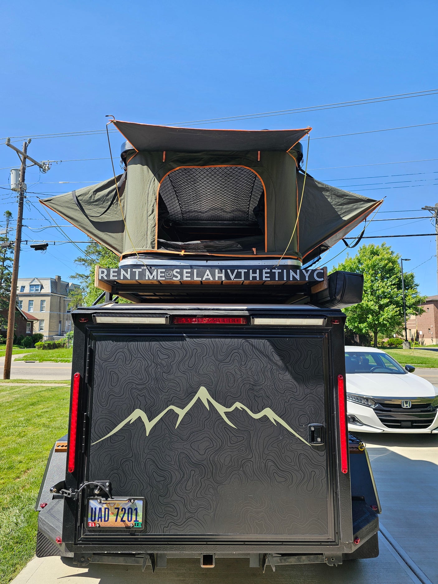Adventure rv rental: Rear view of compact trailer with rooftop tent. Text 'RENT ME SELAHVTHETINYNYC' identifies this unique camping vehicle.