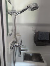 RV rental's compact bathroom includes a shower, sink, mirror, and towels. Functional design for mobile living.
