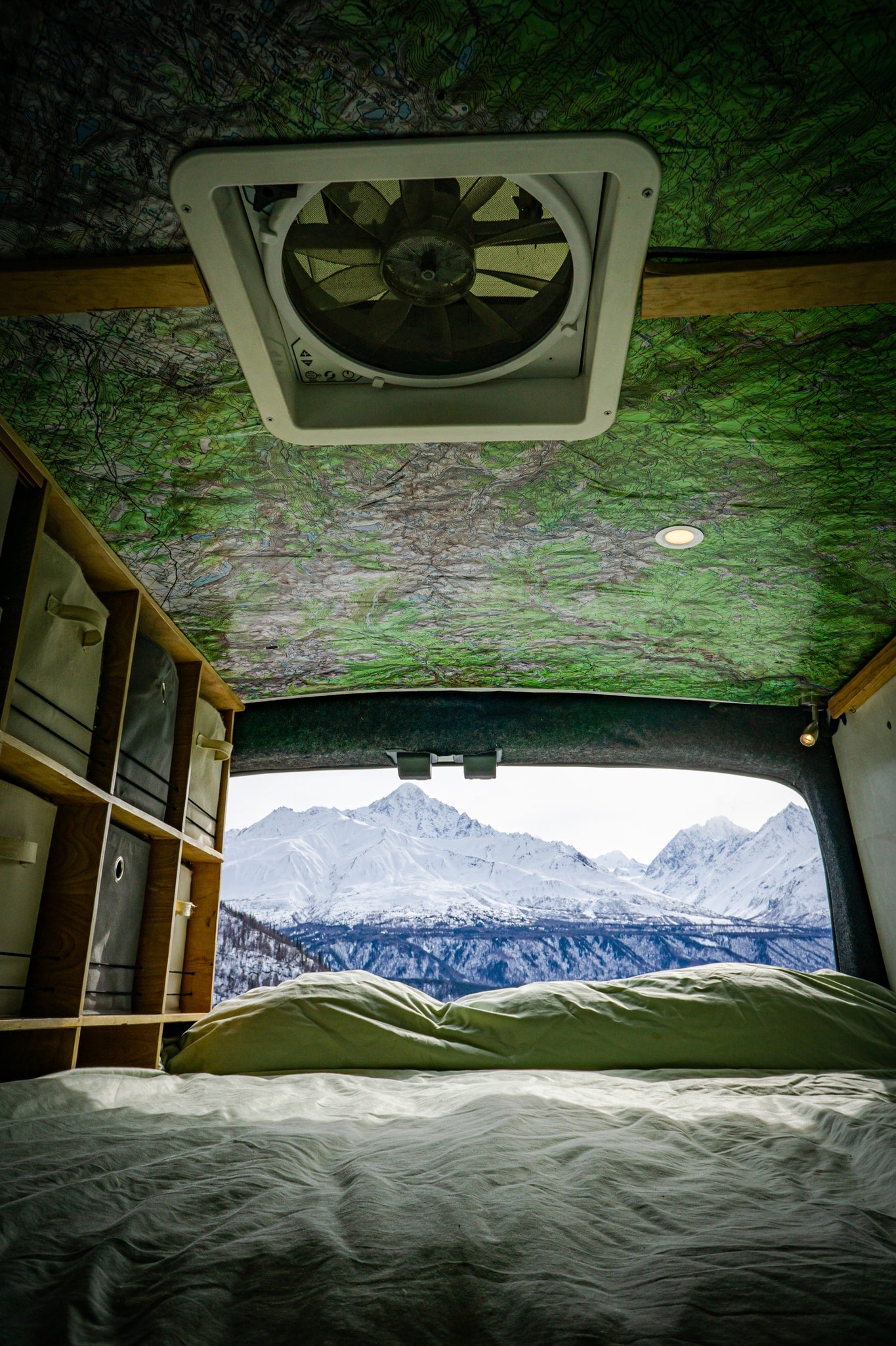 Wake up to stunning views! This rv rental offers a cozy bed, map ceiling, storage, & a vent with snowy mountain vistas. — photo 5