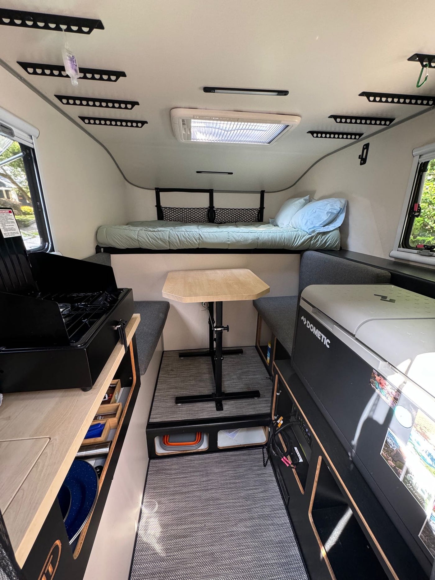 This RV rental interior features a bed, dining space, and kitchenette for comfortable travel. — photo 10