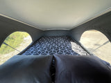 Cozy pop-top bed inside an RV rental, offering comfortable sleeping with scenic views through arched windows.
