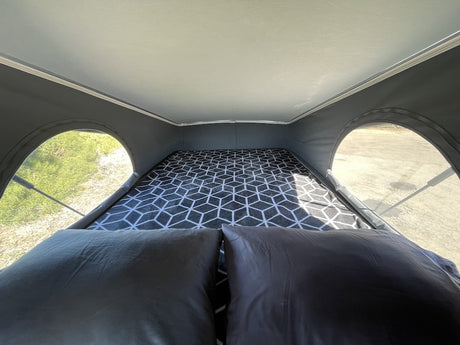 Cozy pop-top bed inside an RV rental, offering comfortable sleeping with scenic views through arched windows.