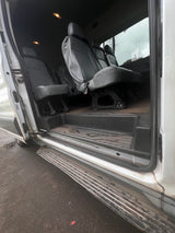 Spacious RV rental interior featuring gray passenger seats, wood-look floor, and wide entry step visible through the open sliding door.