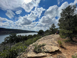 Stunning cliffside lake view with a person meditating. Imagine this peaceful spot on your next RV rental adventure.
