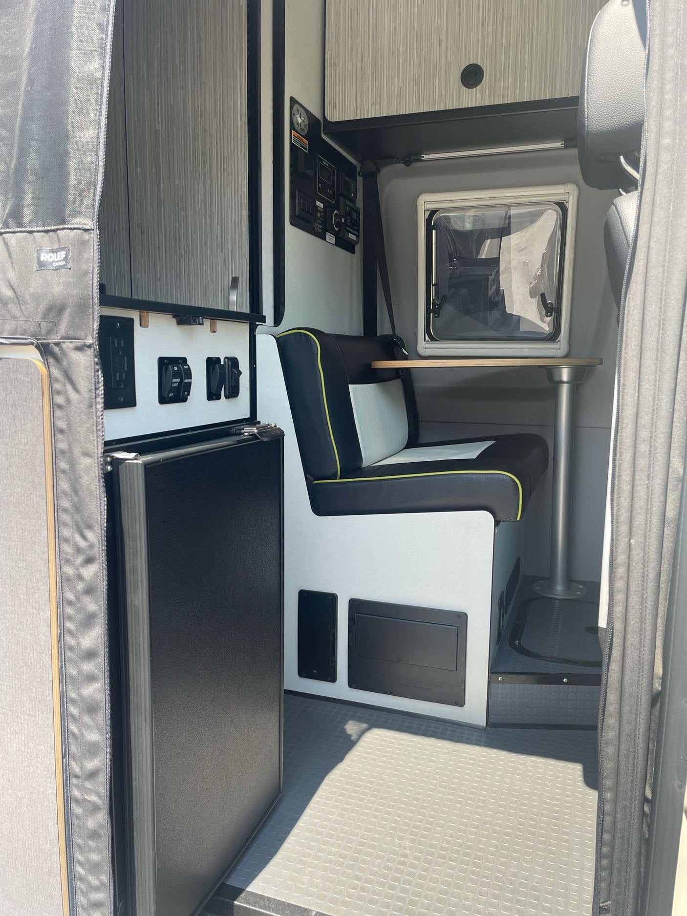 Functional RV rental interior featuring a compact kitchenette with fridge and a dinette with bench seating and a small table.