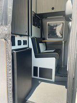 Functional RV rental interior featuring a compact kitchenette with fridge and a dinette with bench seating and a small table.