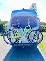 RV rental: White van with two colorful cruiser bikes on a rear rack, ready for sunny adventures.