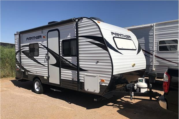 This Panther travel trailer, ideal for your next rv rental, is parked outdoors on a sunny day.