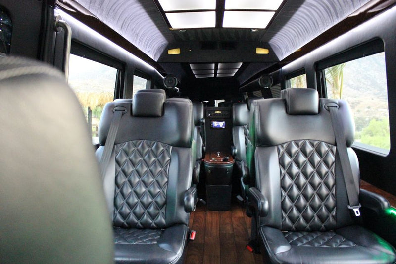  parked on a driveway with mountains and palm trees behind it.|Plush RV rental interior showcasing diamond-quilted leather seating — photo 2