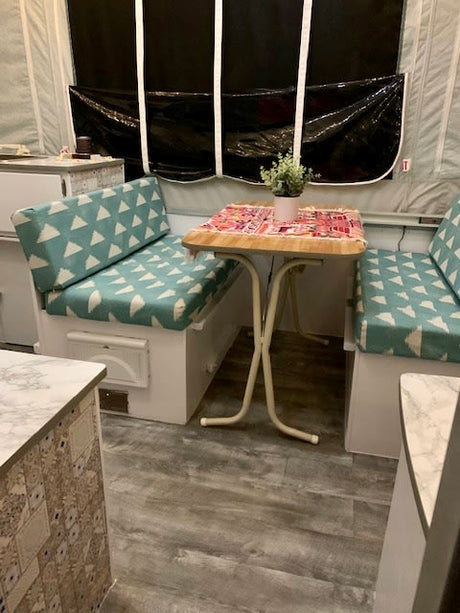 This RV rental features a compact, updated dinette with stylish cushions & a plant, perfect for meals on the road.