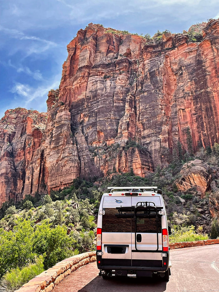  parked alongside towering red rock canyon walls under a clear blue sky.|Scenic drive to El Capitan in Yosemite