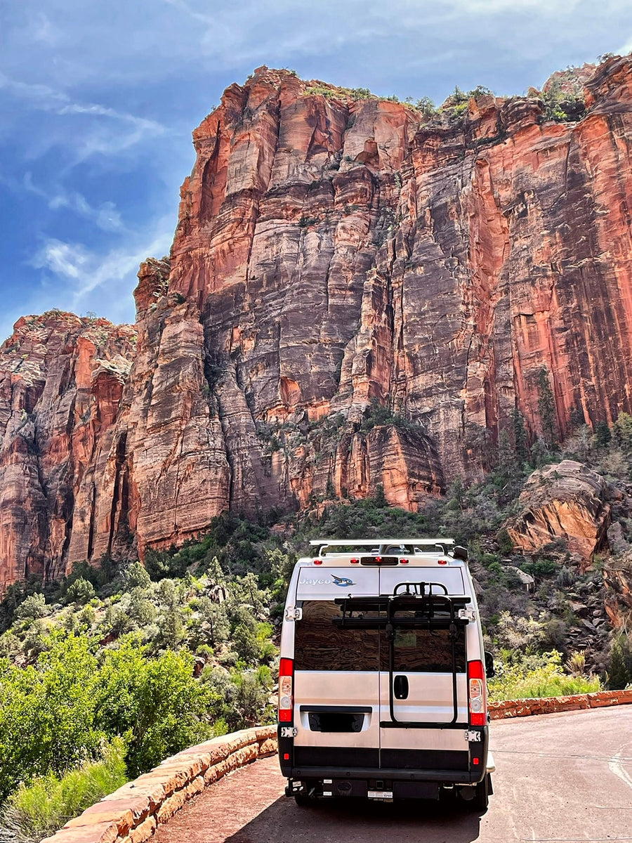  parked alongside towering red rock canyon walls under a clear blue sky.|Scenic drive to El Capitan in Yosemite