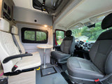 Cozy rv rental interior. Features swiveling passenger seats, a small table, overhead storage, and driver's cockpit view.