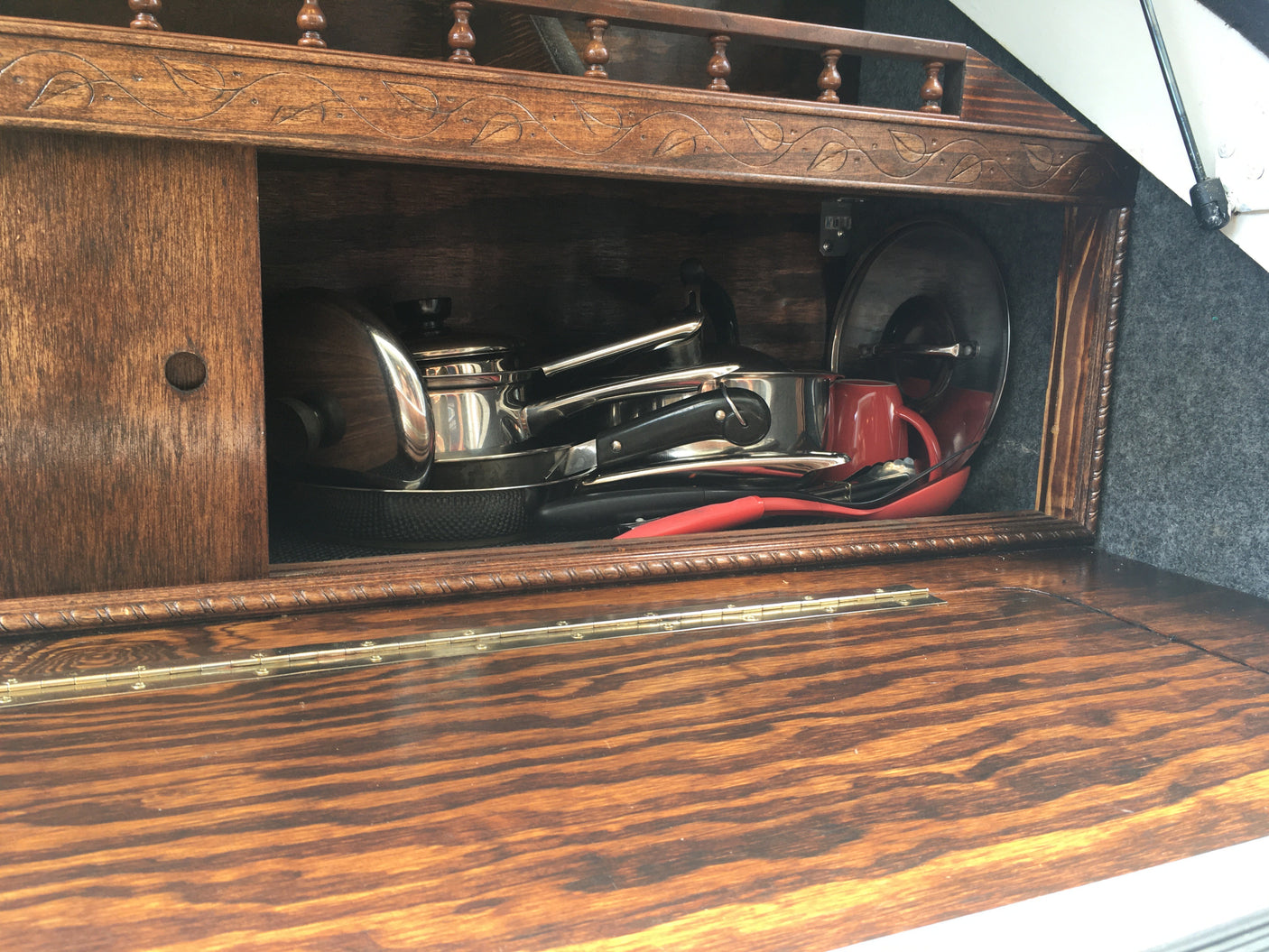 RV rental kitchen: a compact wooden cabinet showcasing neatly stored pots, pans, and utensils, perfect for travel cooking.