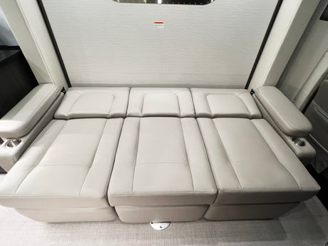 Light gray convertible sofa bed with cup holders in an RV rental, folded flat for sleeping.