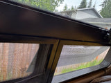 Inside an RV rental, a dark-framed, screened window provides ventilation and a view of the outdoors.