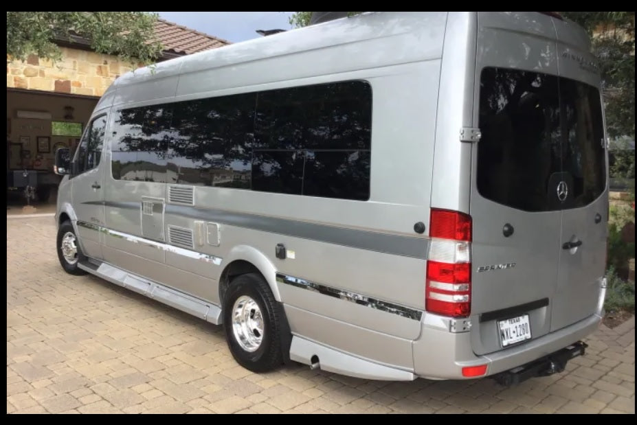 Modern silver Mercedes Sprinter rv rental parked outdoors. This luxury travel van features tinted windows and a rear tow hitch.