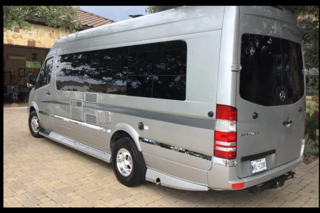 Modern silver Mercedes Sprinter rv rental parked outdoors. This luxury travel van features tinted windows and a rear tow hitch.