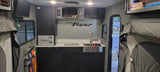 Modern rv rental interior: A compact galley with sink, stovetop, and integrated storage, perfect for your next camper adventure.