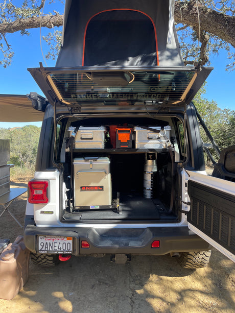 This white Jeep overlanding setup, with a rooftop tent and Engel fridge, is perfect for an adventure-ready RV rental.