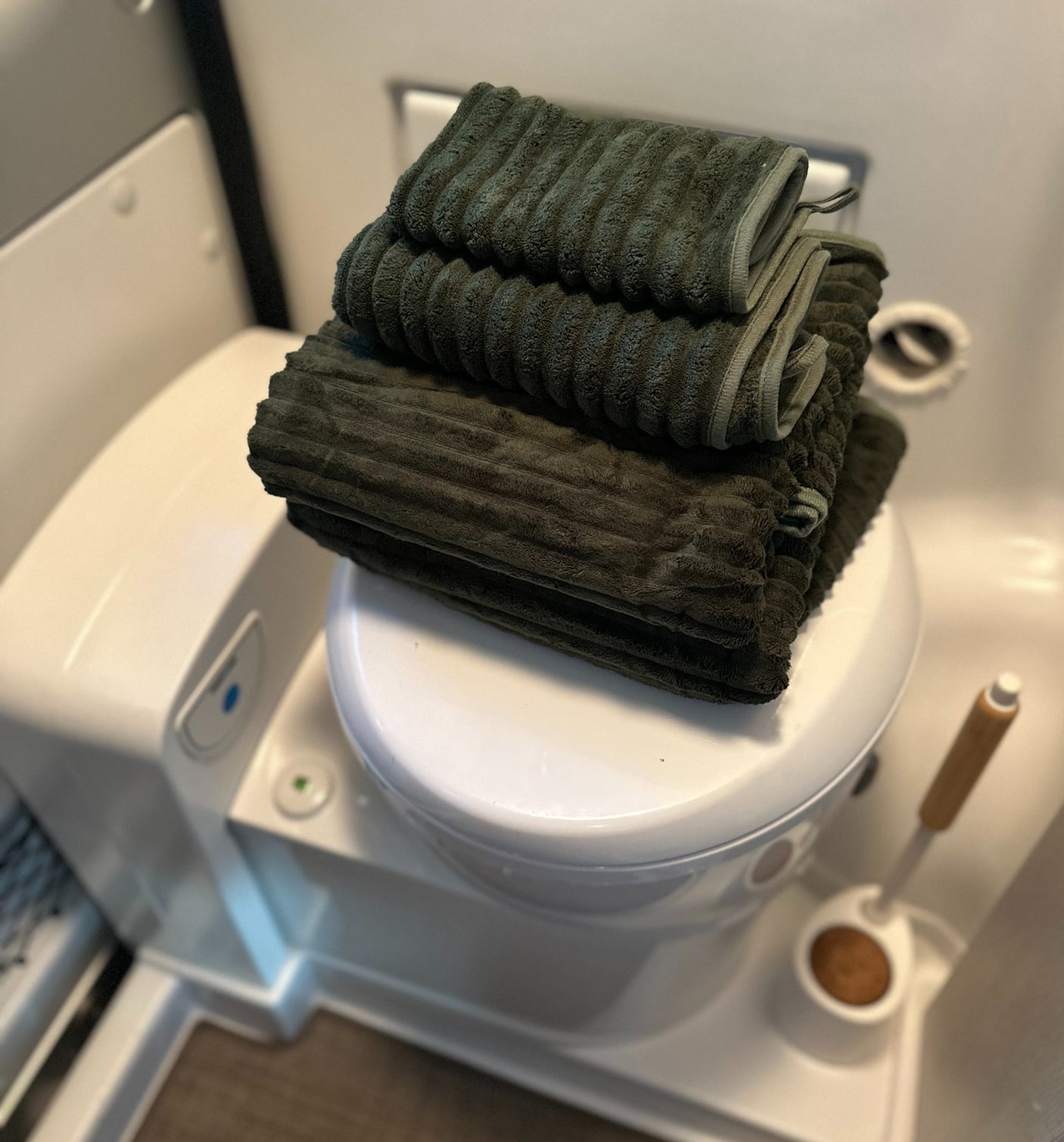 Neatly stacked green towels on a compact RV toilet, ready for your rv rental adventure. A practical detail for comfortable travel.