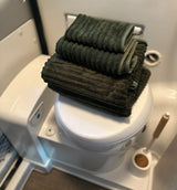 Neatly stacked green towels on a compact RV toilet, ready for your rv rental adventure. A practical detail for comfortable travel.