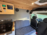 Cozy rv rental campervan interior with wood ceiling, integrated control panel, galley kitchen, and modular bed/seating.