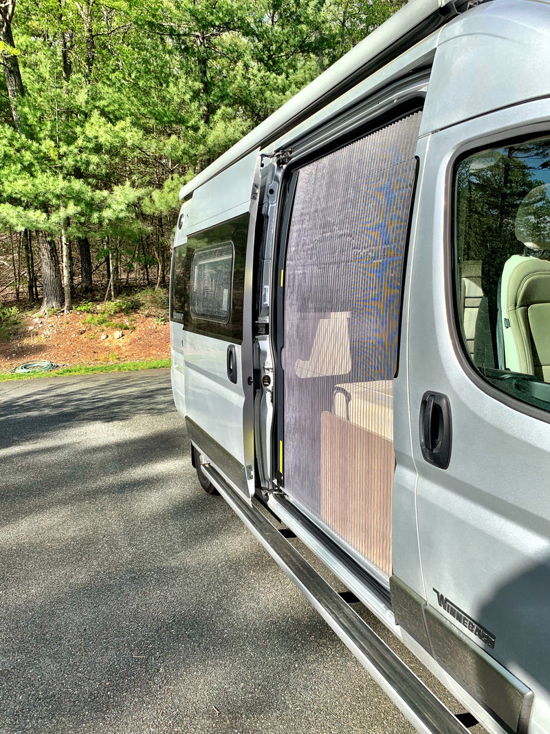 Silver RV rental camper van with open side door and pleated screen, parked on an asphalt lot beside a green forest. — photo 2