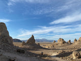 Explore a striking desert landscape with towering tufa formations, distant mountains, and a dirt path. Ideal for an RV rental adventure!