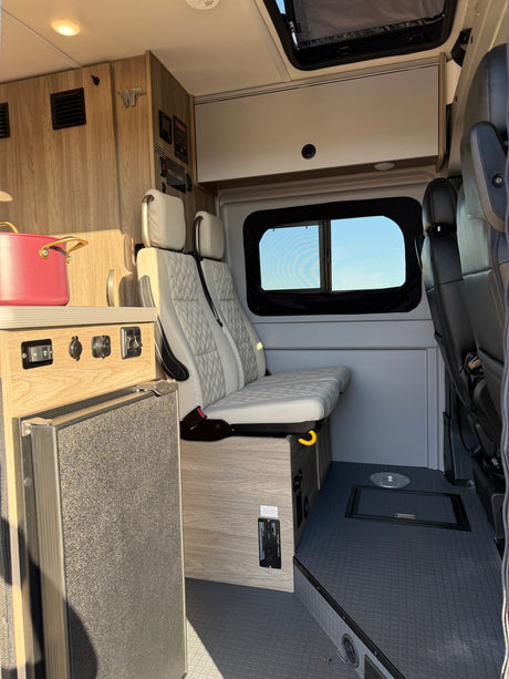 Experience a comfortable RV rental: modern camper van interior with Winnebago branding, quilted seating, and portable fridge.