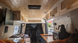 Inside a stylish camper van, great for an RV rental. View towards the front with a kitchen, workspace, and wooden ceiling.