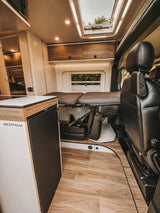 Modern rv rental interior with Westfalia fridge, bed, cabinets & skylight, perfect for your next trip.