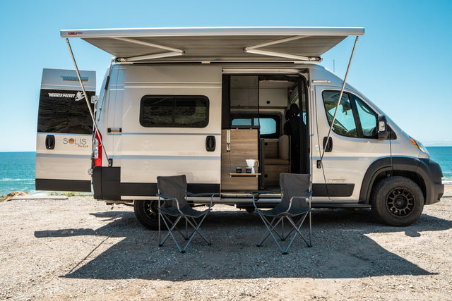 Enjoy this Winnebago Solis Pocket camper van for your next RV rental, featuring an awning & chairs by the ocean.