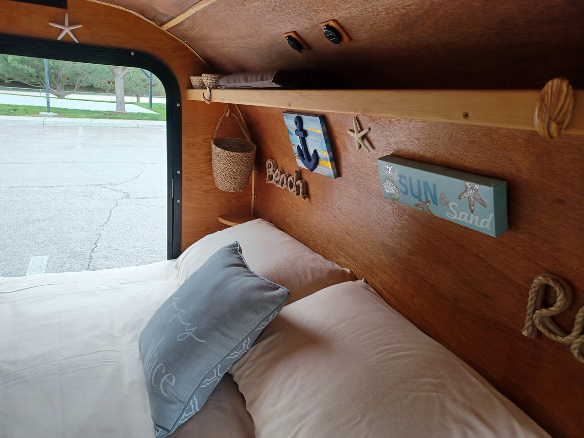 Charming, compact rv rental interior with a cozy bed, nautical decor, and wooden accents, offering a serene escape. — photo 11