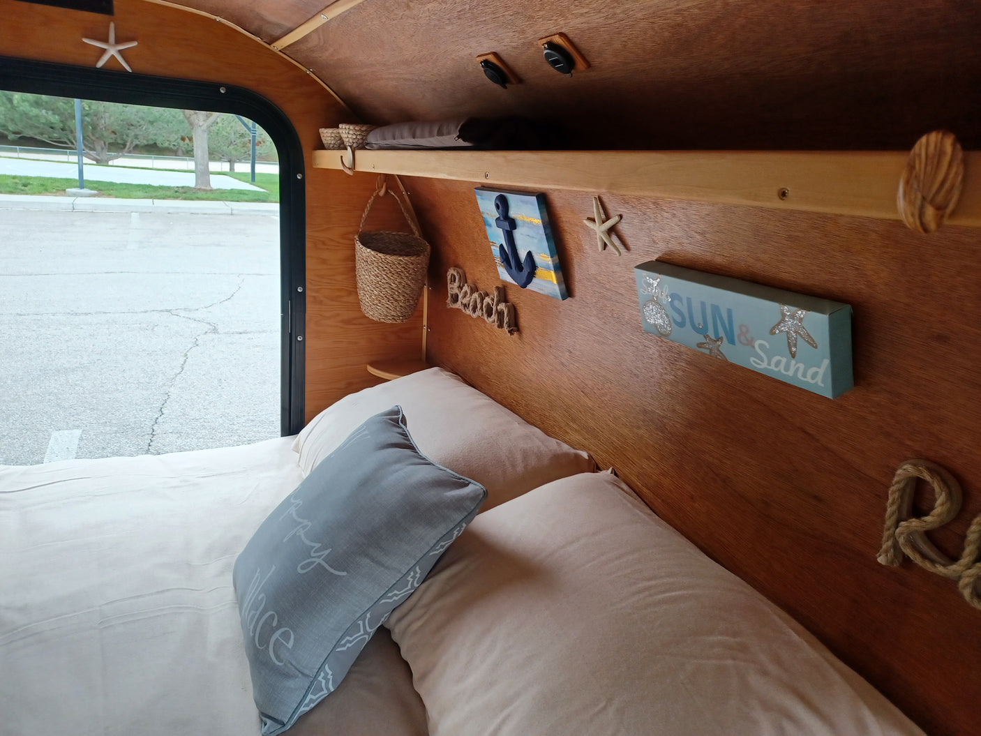 Charming, compact rv rental interior with a cozy bed, nautical decor, and wooden accents, offering a serene escape.