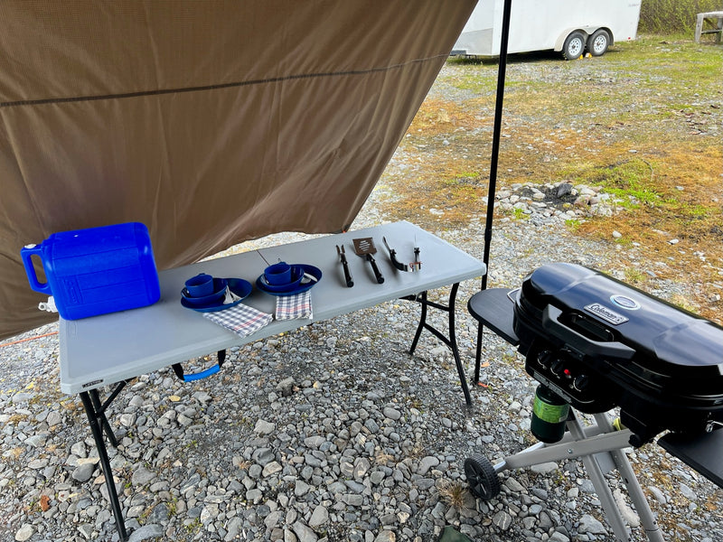 RV rental outdoor kitchen setup: portable grill, table, water jug & dishes under awning. Perfect for camping! — photo 9