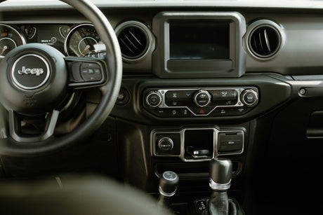 Jeep interior: steering wheel, gauges showing "Brake + Press Brake," & climate/drive controls. Great for an RV rental.