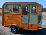 Charming wood and sage green custom camper trailer, an ideal RV rental for your next outdoor adventure.