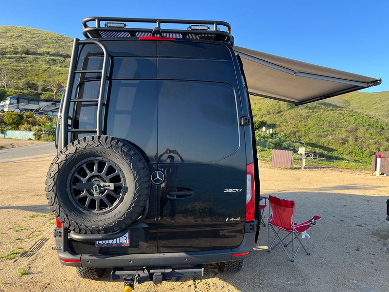 Black Sprinter van, ideal for an RV rental adventure, parked at a scenic outdoor camping spot with its awning extended. — photo 20