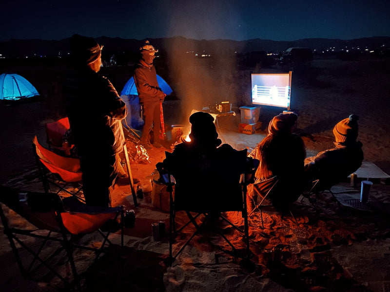Friends enjoy a lively outdoor movie night with a campfire and tents in the desert. The ultimate RV rental adventure! — photo 16