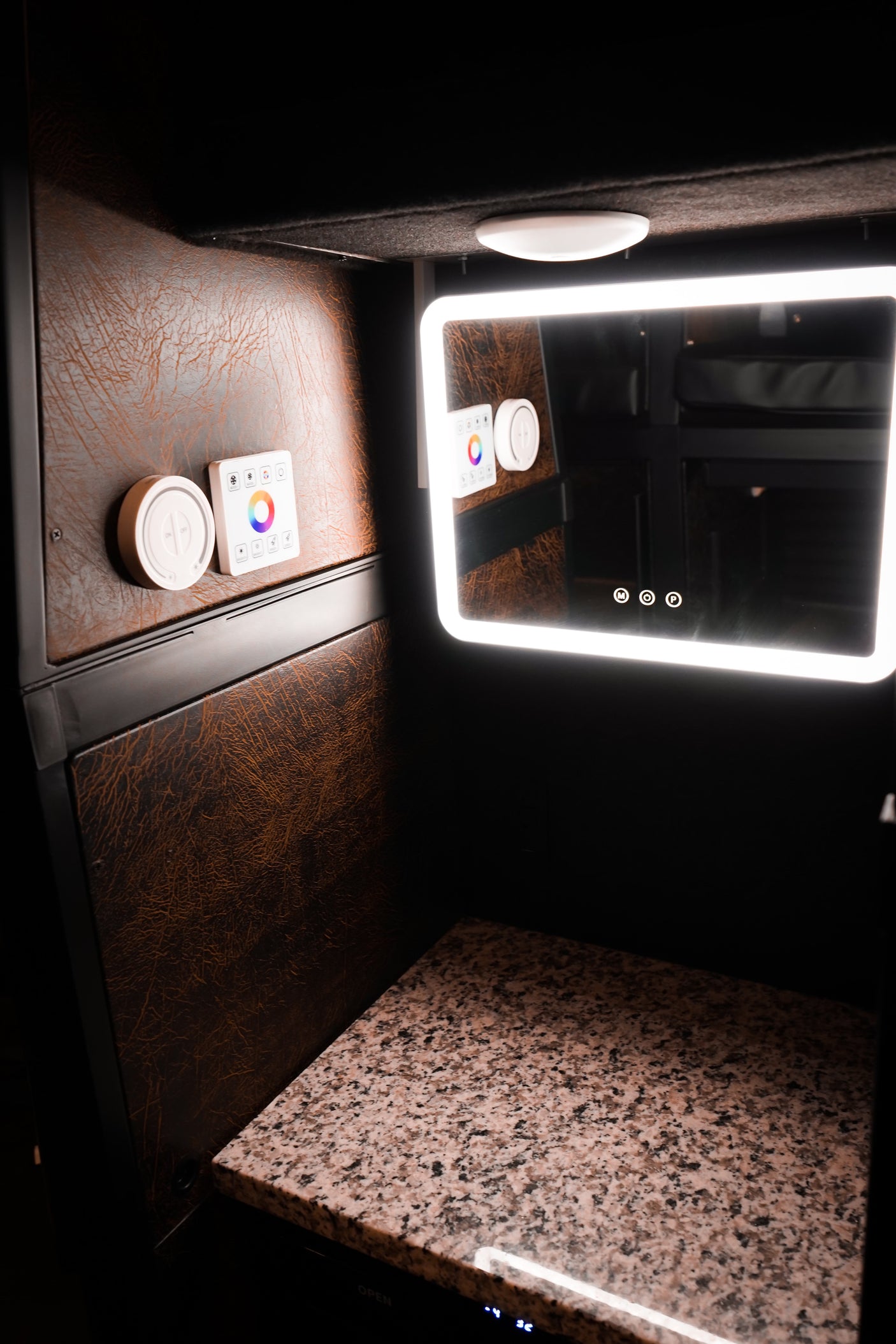 Well-appointed RV rental vanity featuring a lighted smart mirror, tactile controls for ambiance, and elegant granite counter.