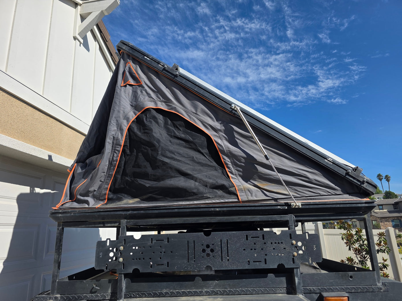 An open gray rooftop tent on an overland vehicle, ideal for an RV rental adventure under a clear blue sky. — photo 6