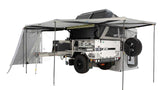 This rugged off-road camper trailer, ideal for RV rental adventures, features an awning, full kitchen, fridge, and rooftop tent.