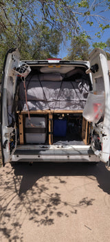White RV rental camper van's rear open, showcasing a comfy bed & under-bed storage for road trips.