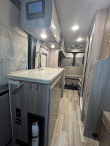 Modern rv rental interior: compact kitchenette with sink, smart control panel, and cozy dinette for mobile living.