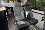 Inside this RV rental: two black passenger seats and an elevated bed, providing flexible seating & sleeping in a camper van.
