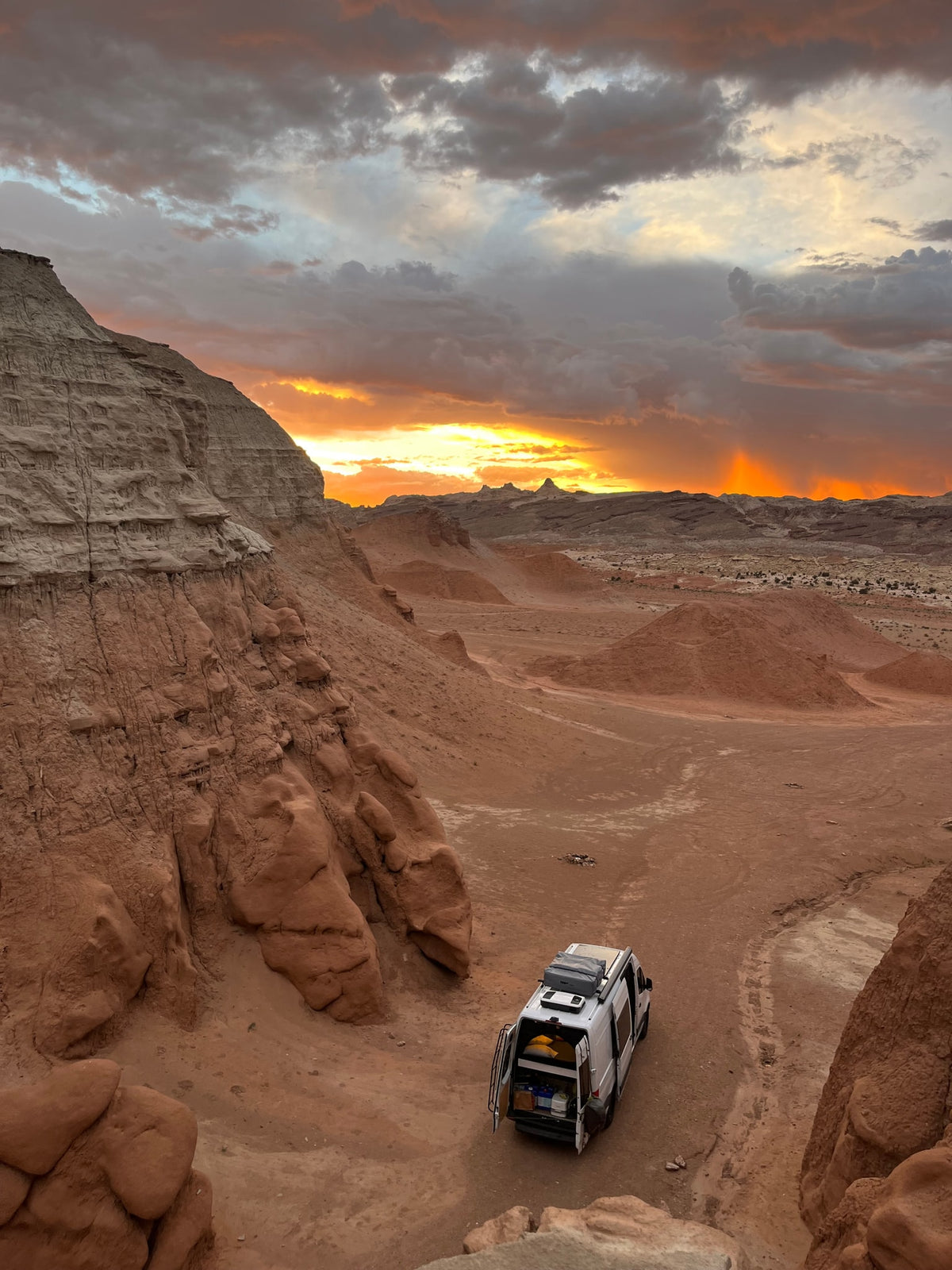 Golden sunset lights a white RV rental parked in a rugged desert valley with towering cliffs. A perfect spot for remote adventure. — photo 14
